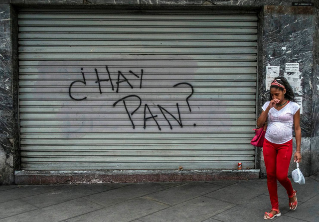 Một phụ nữ đi ngang qua một cửa hàng đóng kín cửa ở Caracas, Venezuela với dòng chữ Có bánh mì không? trên cửa. (Nguồn: Juan Barreto / AFP / Getty Images)