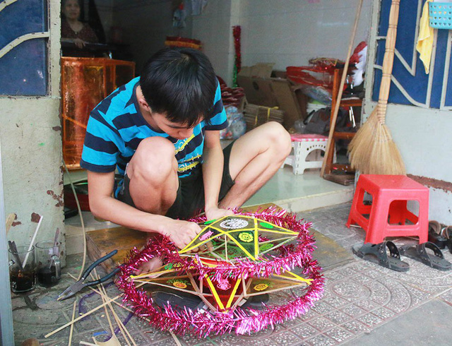 
Anh Nguyễn Trọng Hiệp, em của anh Nguyễn Trọng Thành, dán lại chiếc đèn lồng để giao hàng cho khách hàng.
