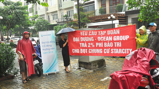 Cư dân chung cư Star City ở 81 Lê Văn Lương đội mưa căng băng rôn đòi quỹ bảo trì. Ảnh: Thanh Niên.