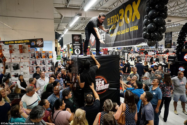 Một nhân viên siêu thị ở Sao Paolo, Brazil đang cố gắng trấn tĩnh lại đám đông dường như đang “vỡ òa” phía dưới. (Ảnh: Rex)