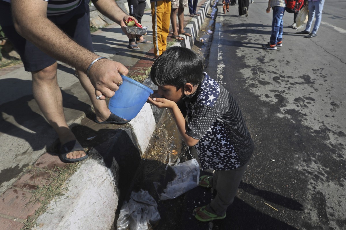 The child of a migrant daily wage labourer who has lost his job is given water by a bystander in India. Photo: AP