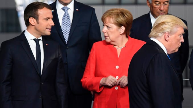 French President Emmanuel Macron (L) and German Chancellor Angela Merkel (2nd L) speaks as US President Donald Trump (C) arrives for a family picture during the NATO (North Atlantic Treaty Organization) summit at the NATO headquarters, in Brussels, on May