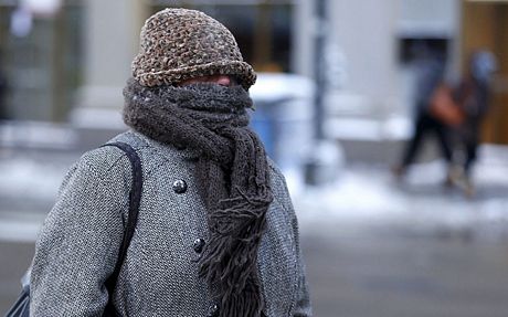 Một phụ nữ cố gắng giữ ấm bằng cách trùm kín người và trừ đôi mắt khi đi ra ngoài đường.
