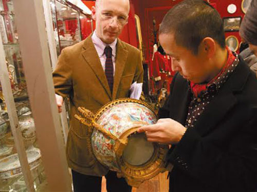 Một khách hàng Trung Quốc xem xét đồ cổ tại nhà đấu giá Drouot ở Pháp Ảnh: CHINA DAILY