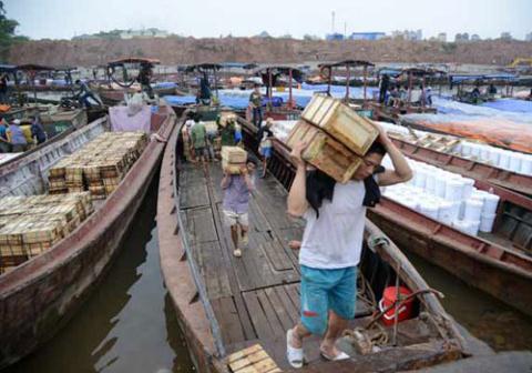 Thương nhân Trung Quốc vận chuyển hàng hóa từ cửa khẩu vào Việt Nam. Ảnh: China Daily