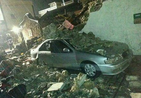 Một chiếc ô tô nằm giữa đống đổ nát của một ngôi nhà sau khi máy bay rơi xuống.