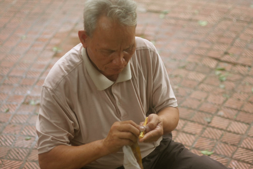Ông Quý ngồi hành nghề khắc bút bên Hồ Gươm