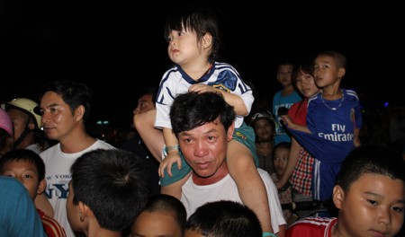 Một em nhỏ được bố cõng trên cổ xem múa lân