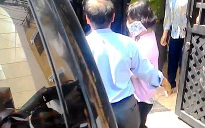 Lê Nguyễn Thị Ái Trâm (che khẩu trang) bị áp giải ra khỏi nhà riêng.