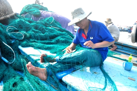 Ngư dân trên tàu cá QNg 94537TS của ông Ngô Tiên (Quảng Ngãi) tranh thủ vá lại lưới
