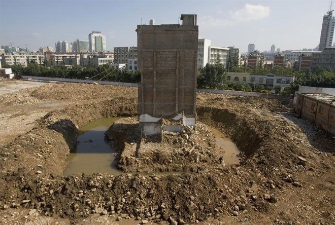 Ông Zhao Xing, 58 tuổi, lấy nước gần ngôi “nhà đinh” đã bị phá một phần của ông trên công trường một dự án ở Côn Minh, Vân Nam, Trung Quốc ngày 30/10/2010 - Ảnh: Reuters.