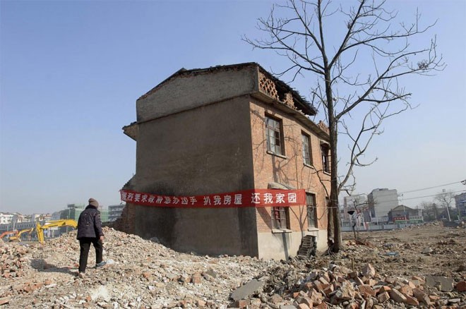 Một “nhà đinh” nằm trong khu dự án chung cư ở Hợp Phì, An Huy, Trung Quốc ngày 3/1/2008. Băng-rôn treo trên ngôi nhà viết: “Đề nghị chính quyền trừng trị chủ đầu tư phá nhà của tôi. Trả lại nhà cho tôi” - Ảnh: Reuters.