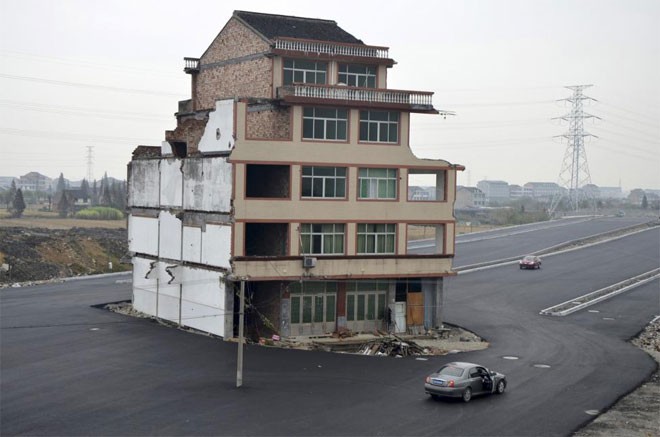 Một “nhà đinh” nằm giữa một con đường mới làm xong ở Wenling, Triết Giang, Trung Quốc ngày 22/11/2012. Một cặp vợ chồng già từ chối ký vào thỏa thuận để chính quyền phá dỡ ngôi nhà của họ với lý do tiền bồi thường không đủ để họ xây nhà mới - Ảnh: Reuters/China Daily.