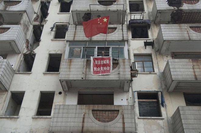 Xu Aiguo, chủ một “nhà đinh” vẫy quốc kỳ Trung Quốc trên ban-công căn nhà ở Nanjing, Giang Tô, Trung Quốc ngày 8/11/2010 - Ảnh: Reuters.