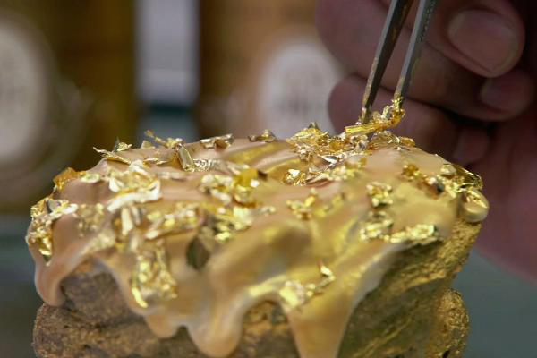 Đầu bếp dùng nhíp gắp từng lá vàng 24k để trang trí chiếc bánh. (Nguồn: CNBC)