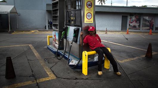 Một nhân viên ngồi thất thần tại trạm xăng Petroleos de Venezuela tại Caracas, Venezuela. (Nguồn: Wil Riera | Bloomberg | Getty Images)