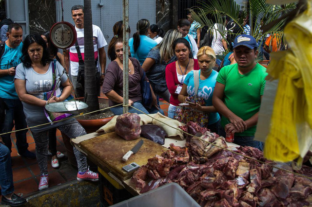 Người dân đứng xếp hàng để mua thịt không rõ nguồn gốc trên đường phố ở thủ đô Caracas. (Nguồn: Wil Riera / Bloomberg)