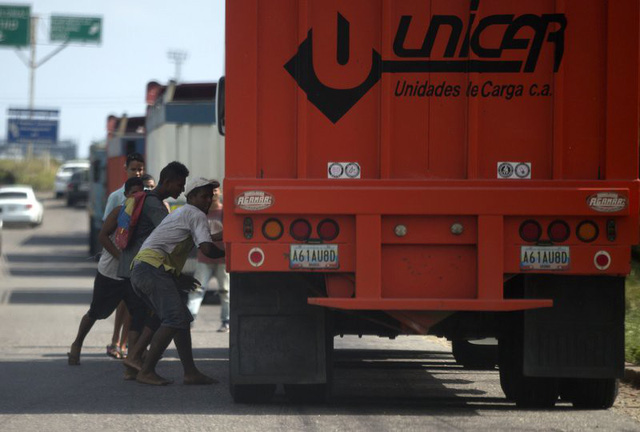 Những người đàn ông đang cố cướp gạo từ một chiếc xe tải chở lương thực trên đường đến cảng Puerto Cabello, Venezuela. (Nguồn: AP/REX/Shutterstock)