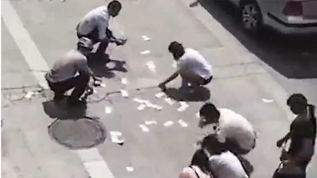 Người dân địa phương thi nhau nhặt tiền rơi trên đường. (Nguồn: bjnews.com.cn)